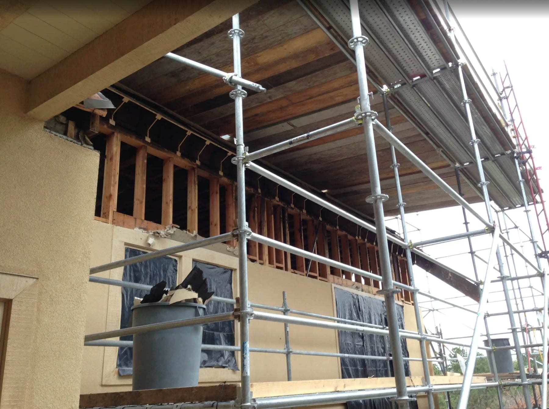 Scaffolding against a house whose exterior wall has been opened for repair